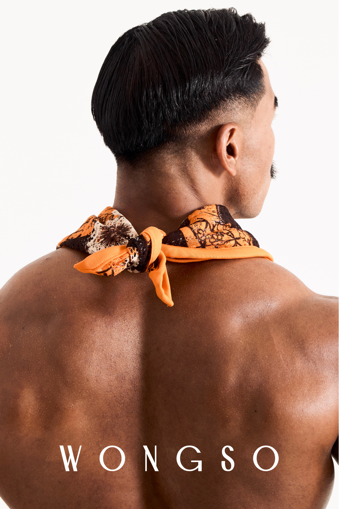 Close-up detail of the sheer orange floral fabric and knot of a men's festival bandana.