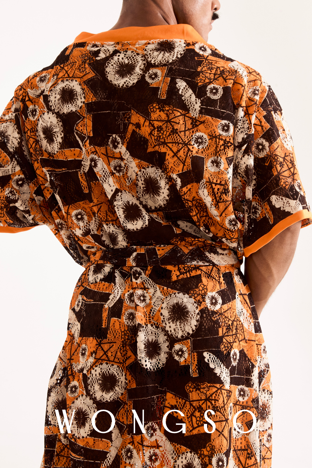 Close-up detail of the sheer orange floral lace fabric and orange trim on a men's festival kimono.