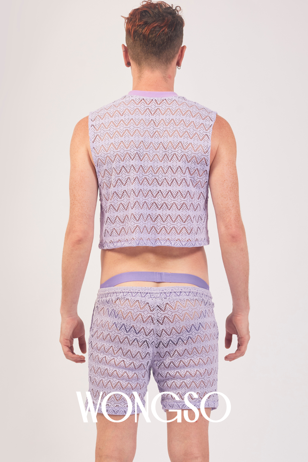 Queer model posing in lilac mesh crop top