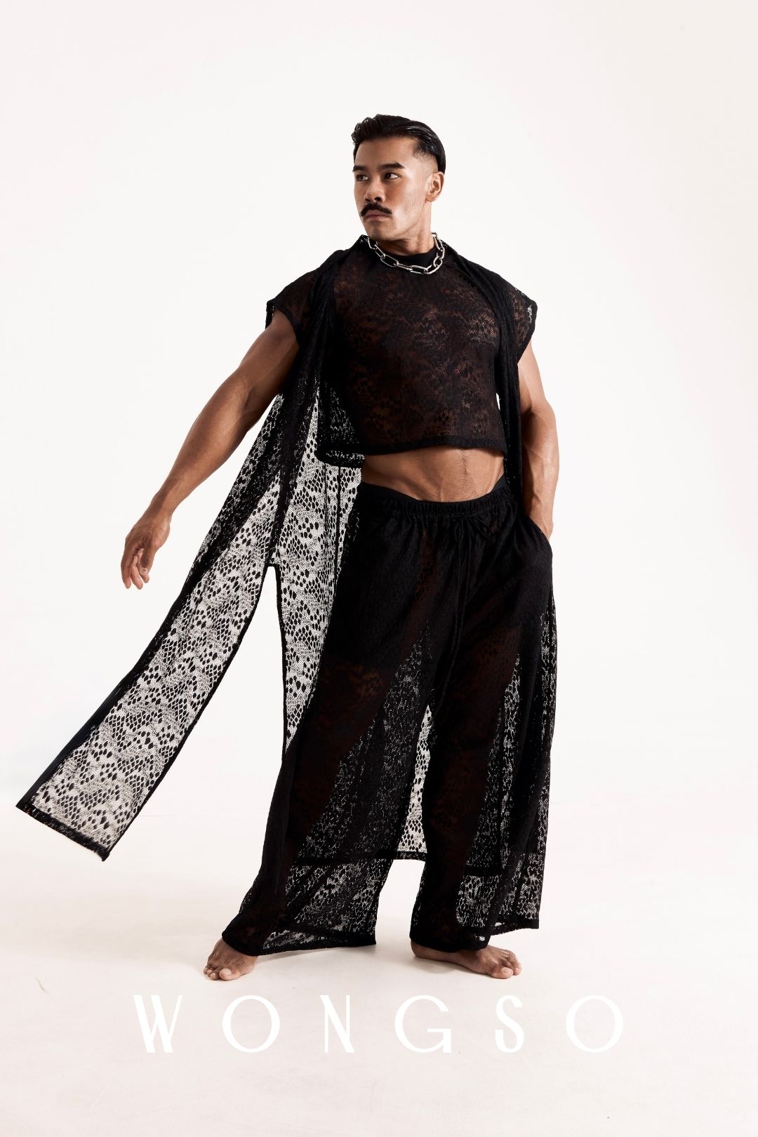 Full outfit shot of a male model wearing the WONGSO Coven collection - leopard print lace kimono, crop top, wide leg trousers and chain necklace. Men's queer festival fashion.