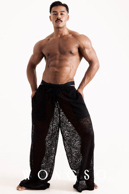 Full body front view of a male model wearing the Libertine Wide Leg Lace Trousers in Leopard Black by WONGSO, billowing sheer silhouette. Men's leopard print festival trousers.