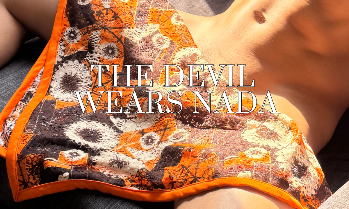 A male model wearing the WONGSO Devil Wears Nada sheer sunset orange floral festival collection, featuring a sheer kimono, wide trousers, and relaxed shirt in a sunset setting. 