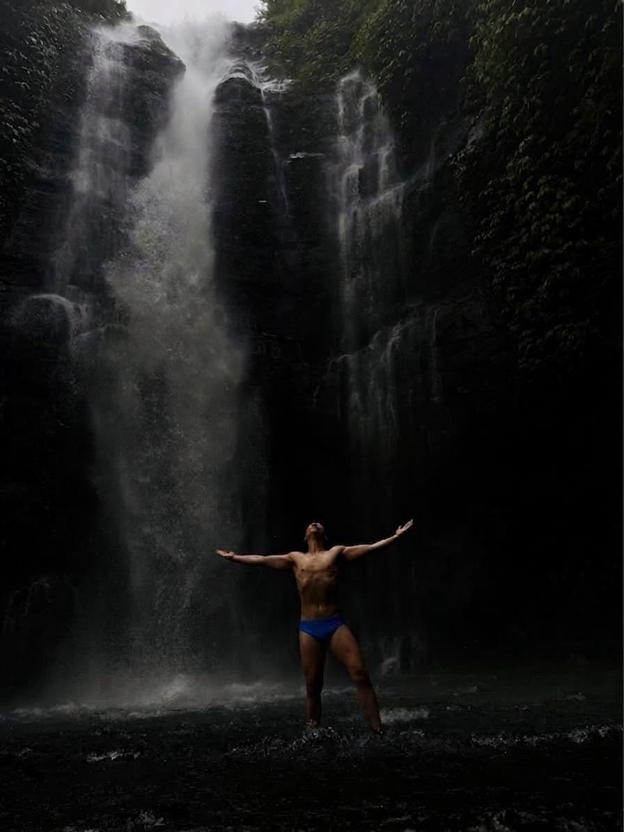 Model in the Bali Blue jockstrap at a waterfall, arms outstretched