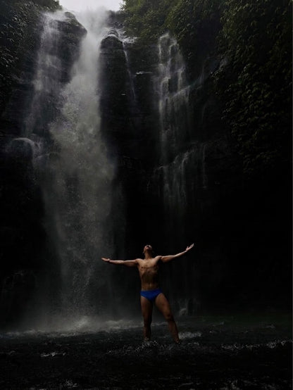 Model in the Bali Blue jockstrap at a waterfall, arms outstretched