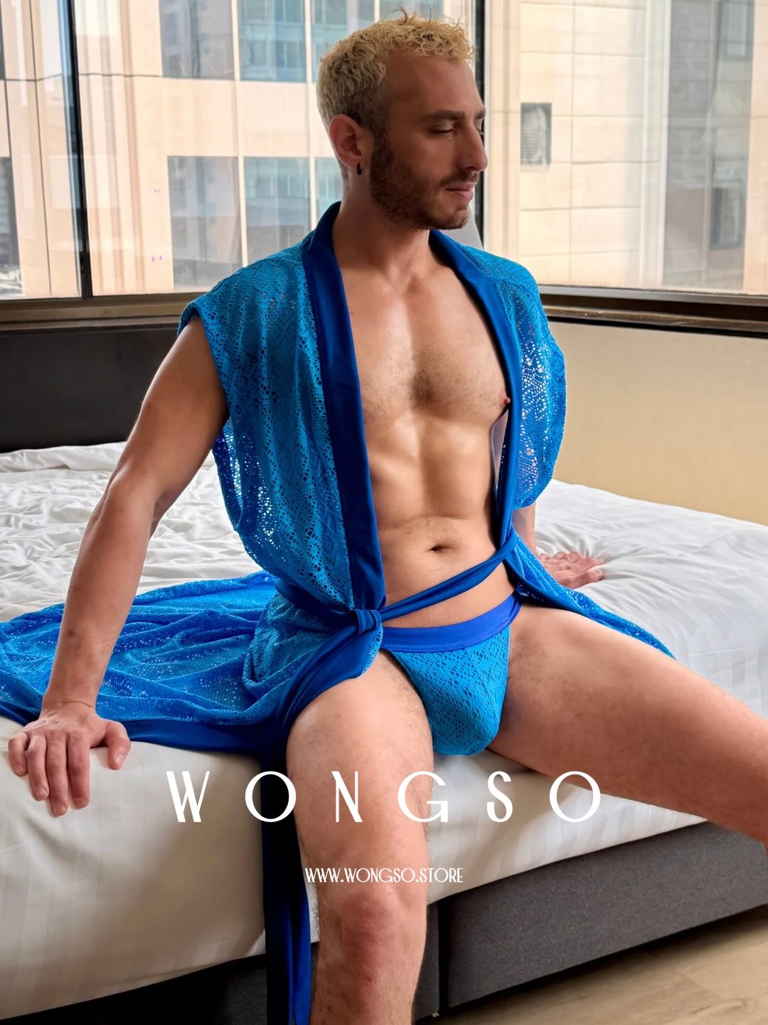 Model in the Bali Blue lace robe seated on a bed