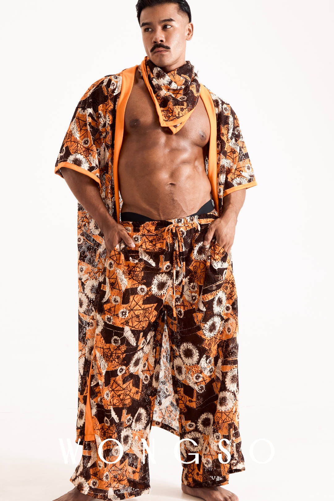 Full body shot of a male model posing in the complete WONGSO sunset orange sheer floral festival set, including kimono and wide trousers