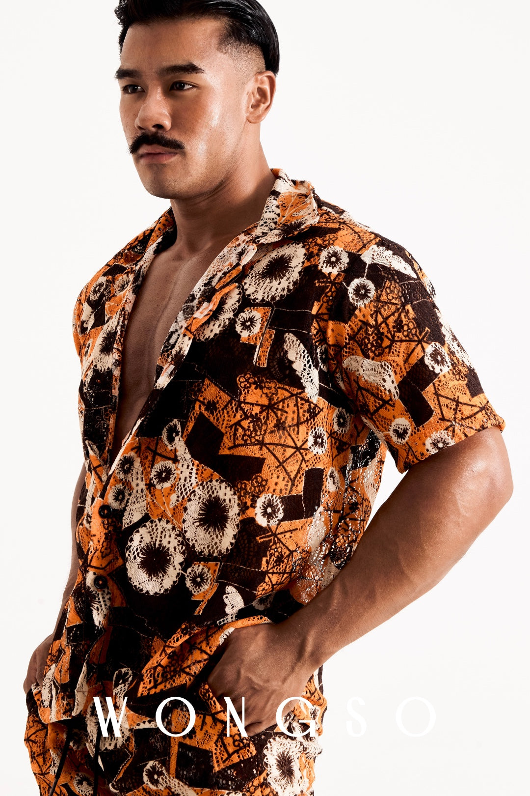 Male model posing in a sheer sunset orange floral WONGSO shirt and matching shorts