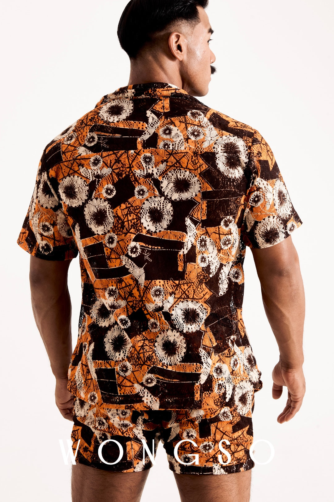 Back view of a man wearing a sheer orange floral relaxed fit festival shirt from the WONGSO Boheme collection