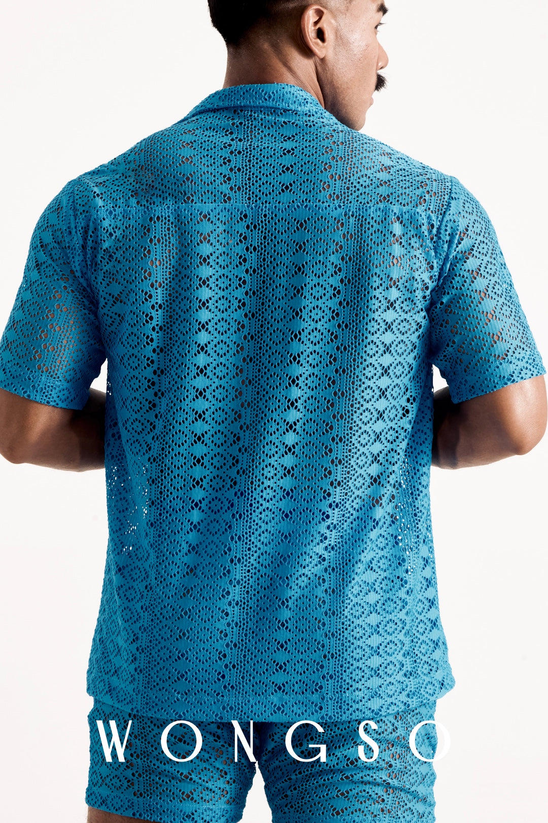 Close-up detail of the sheer blue lace WONGSO shirt, showing the geometric lace pattern and drape