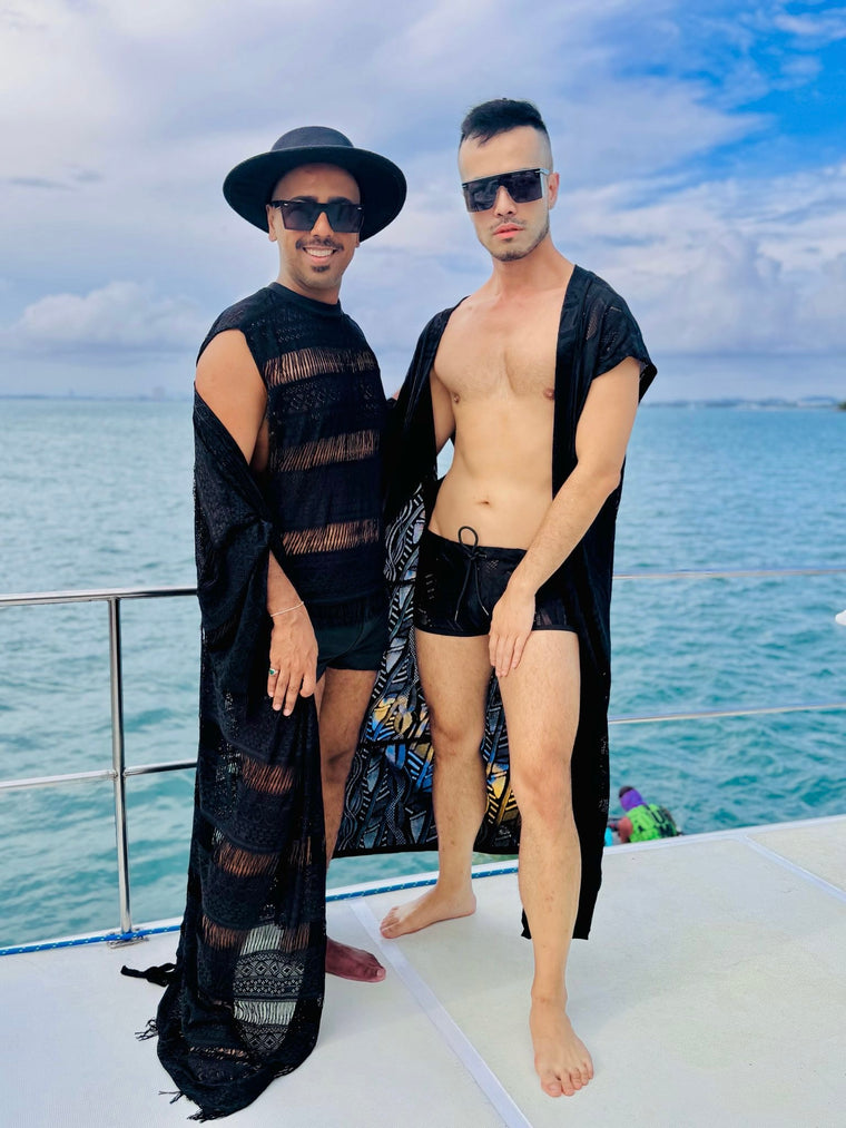 Two friends in black lace kimonos from WONGSO on the deck of a boat party over turquoise water